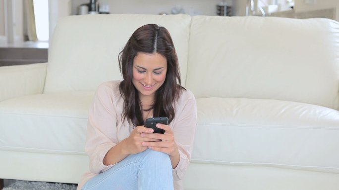 女人坐在客厅的地板上发短信特写