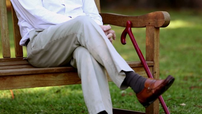 一位老人坐在公园的长椅上休息特写