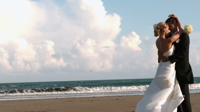 美丽的新婚夫妇在海滩上拥抱的慢镜头