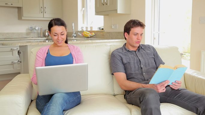女人在沙发上网上购物，向丈夫要信用卡