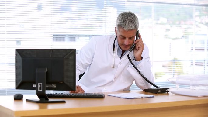 医生打电话用电脑远程会诊主任室独立办公病