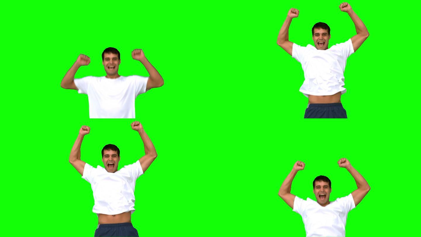 一个快乐的男人在绿色的慢镜头中举起手臂