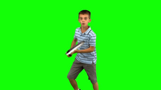 小男孩在绿色背景下练习打网球特写