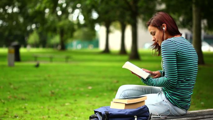 一个学生坐在长椅上看书特写