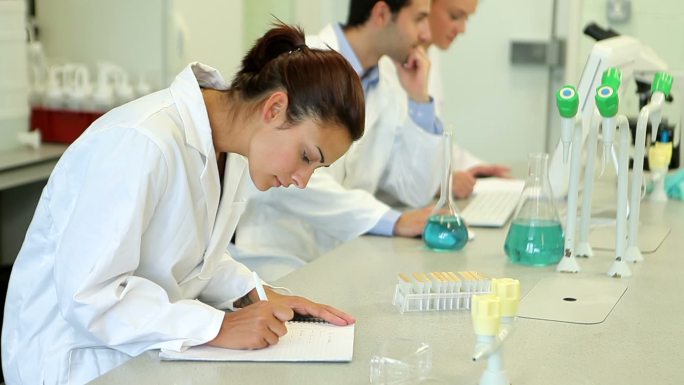 化学家们在实验室里观察烧杯里的液体特写