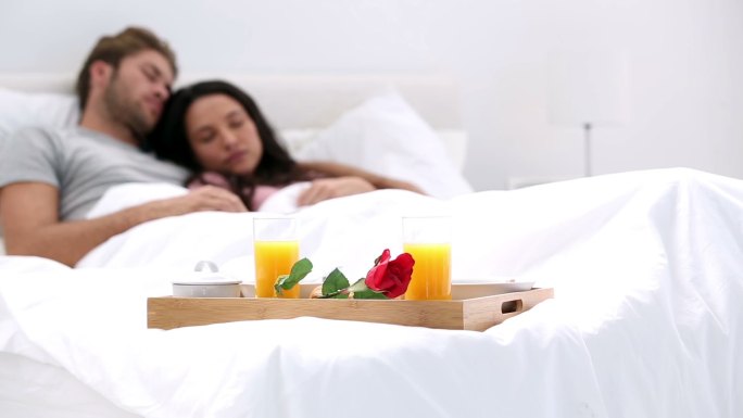 Couple napping after breakfast in bed at home with