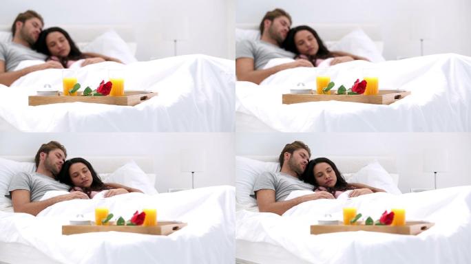 Couple napping after breakfast in bed at home with