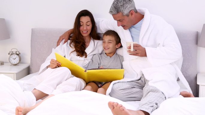 父母和他们的儿子躺在床上读故事