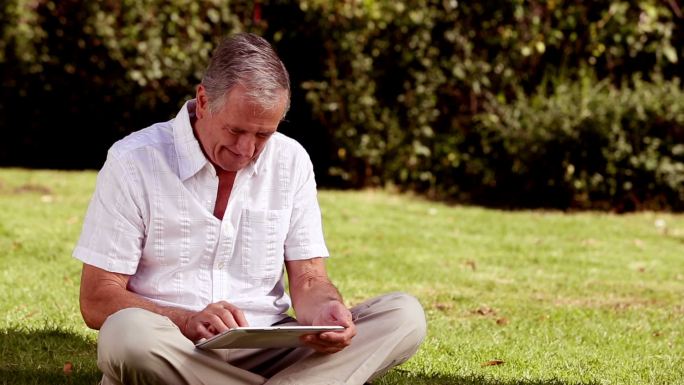 一位老人坐在草地上看书特写