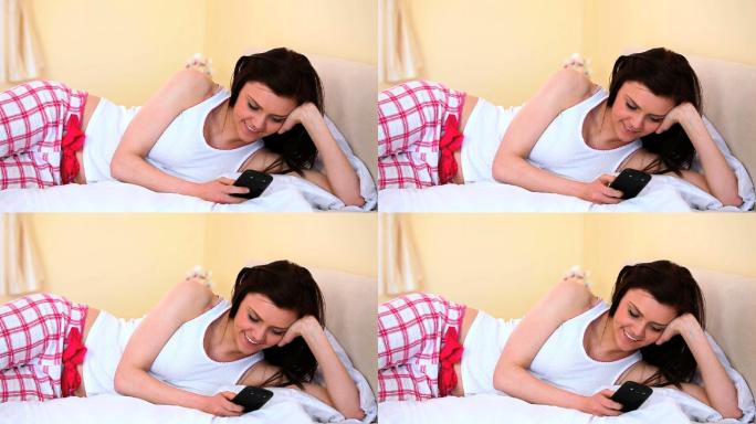 乐呵呵的女人躺在床上看着摄像头发短信
