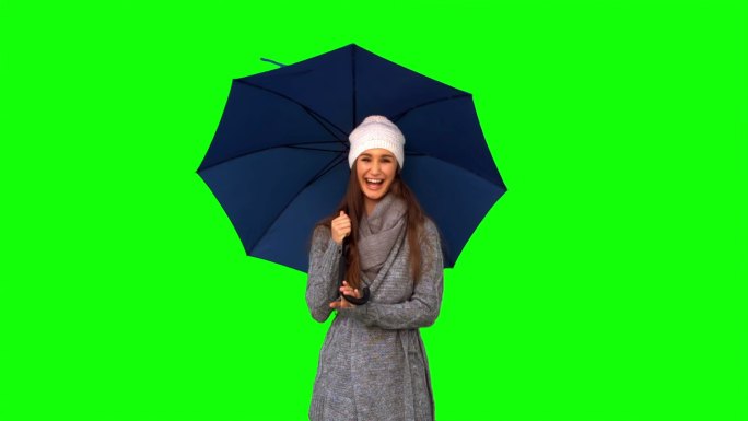 女人穿着冬装站在绿色背景下打伞特写
