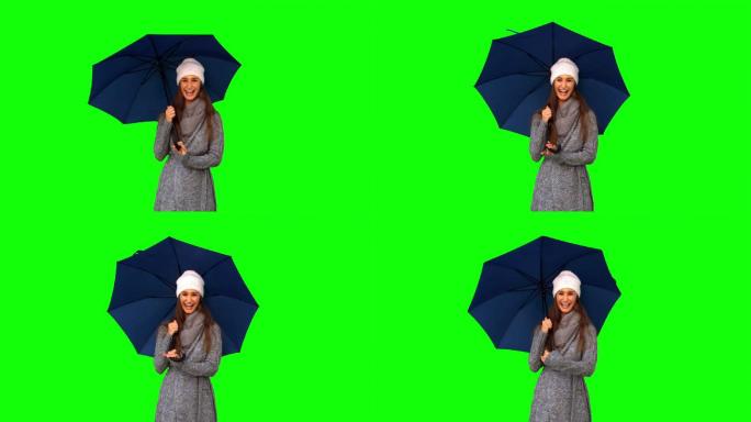 女人穿着冬装站在绿色背景下打伞特写