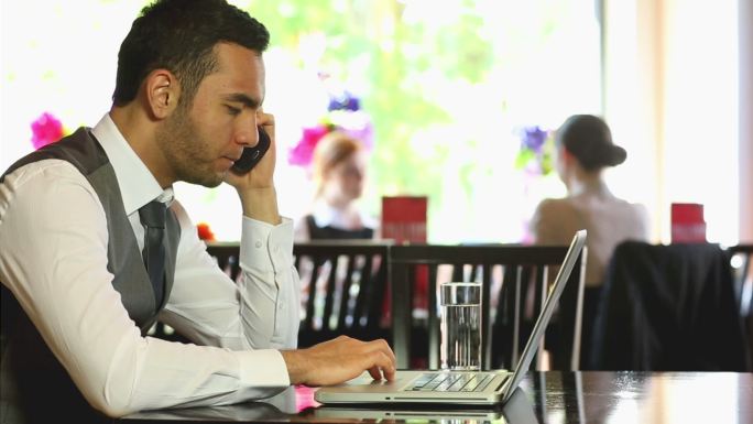 帅气的商人在高档餐厅里用笔记本电脑工作