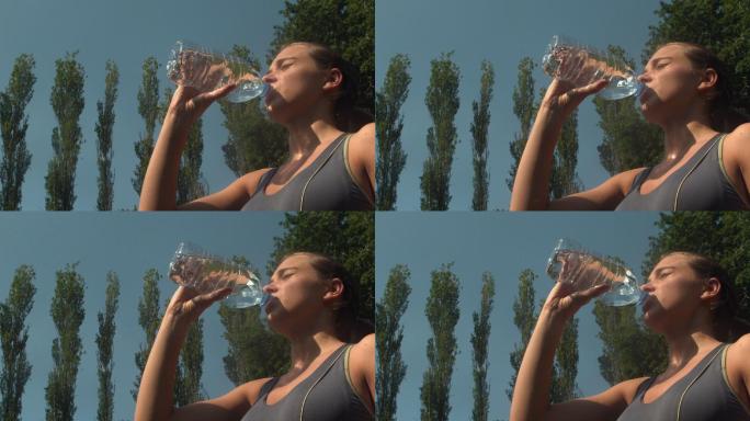 运动运动的女人在一个公园喝一瓶水在慢动作