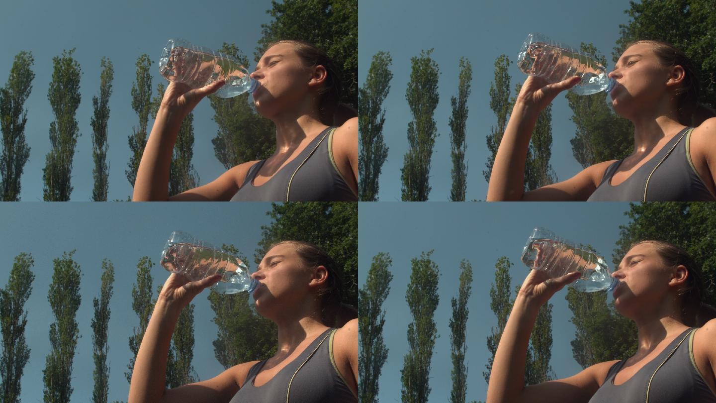 运动运动的女人在一个公园喝一瓶水在慢动作