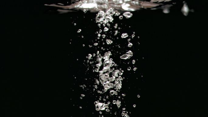 气泡在黑色背景下以超慢的动作进入水中