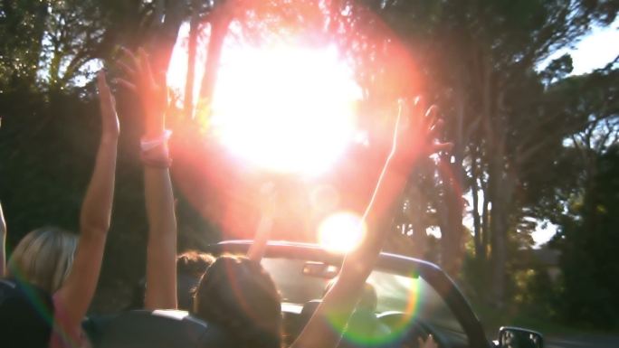 当人们在慢镜头中开车时，快乐的朋友们举起了手
