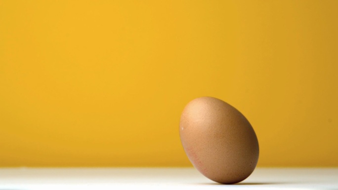 鸡蛋在黄色背景下翻滚特写