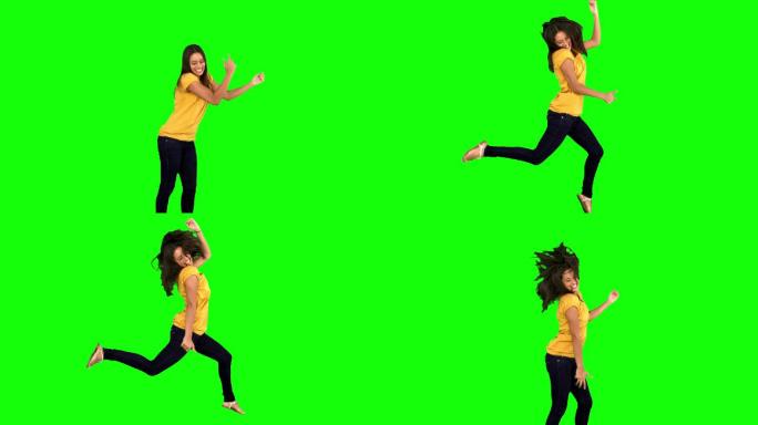 女人在绿色背景下举起手跳跃特写