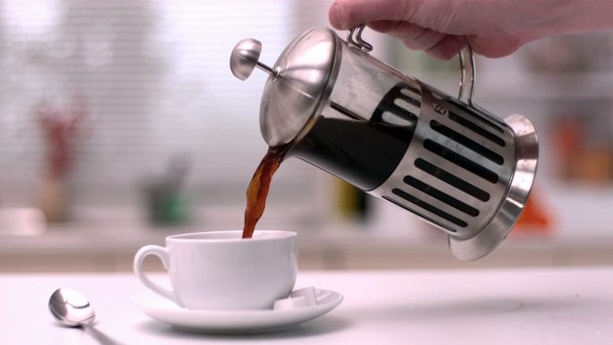 将咖啡从咖啡壶倒入白色杯子里特写