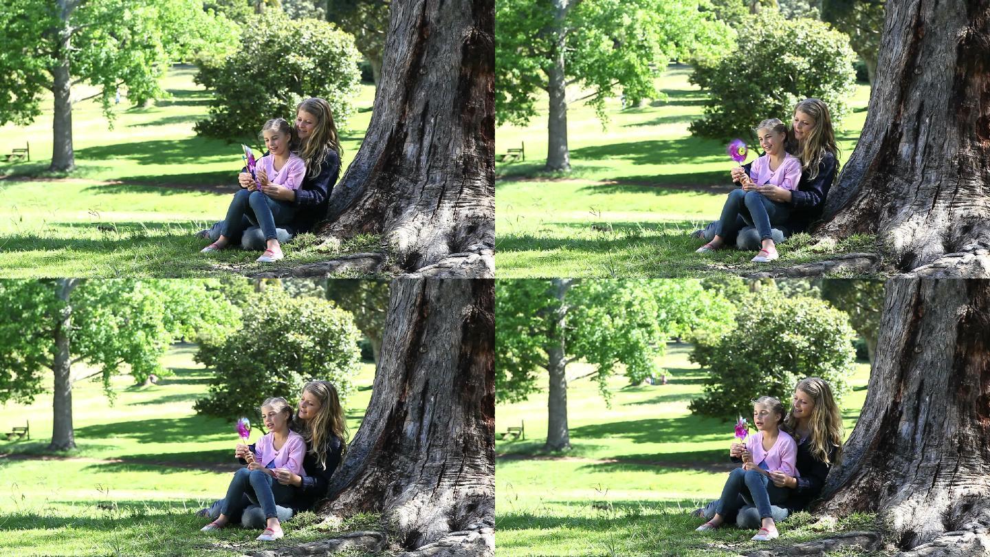 妈妈陪女儿在公园里吹风车特写
