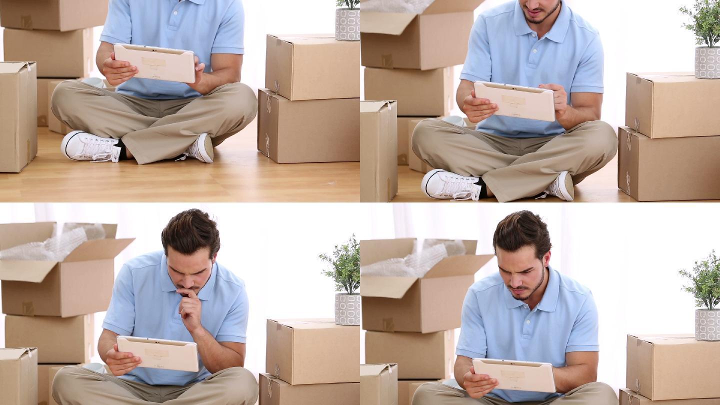 有魅力的男人在移动的箱子中使用数码平板电脑