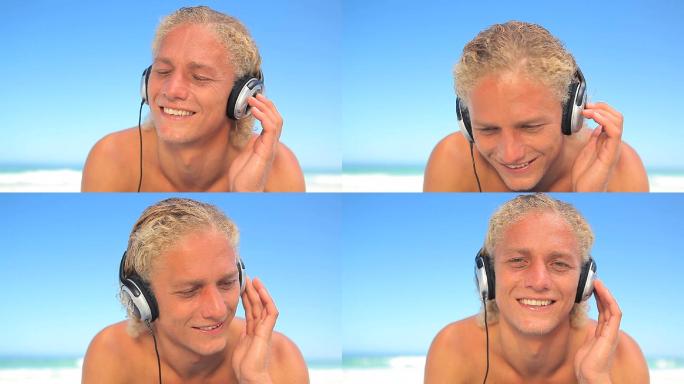 金发男人戴着耳机在海滩上听音乐