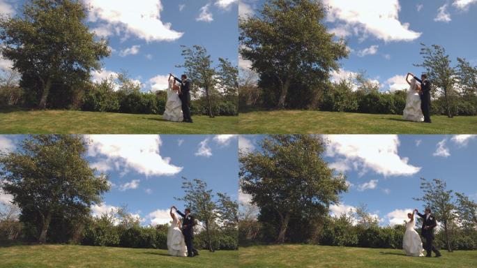 一对快乐的新婚夫妇在公园里用慢镜头跳舞