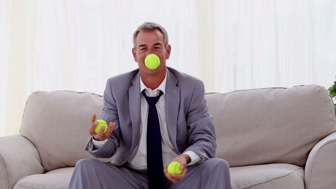 坐在沙发上扔网球的男人特写