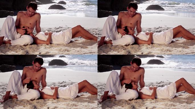 一个女人把头靠在男友的膝盖上，在海滩上放松