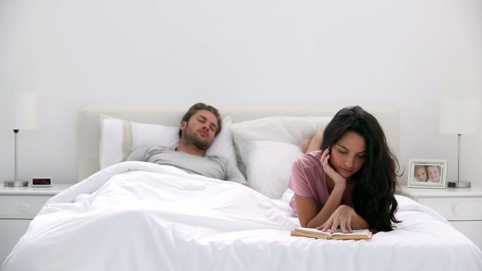 当伴侣在家里的床上睡觉时，女人正在看书