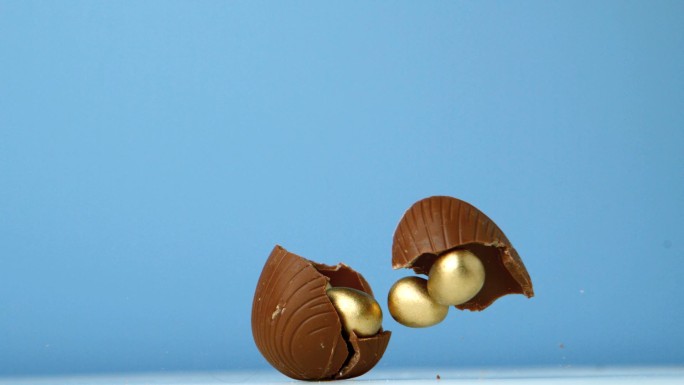 在慢镜头中，巧克力彩蛋在蓝色背景下落下