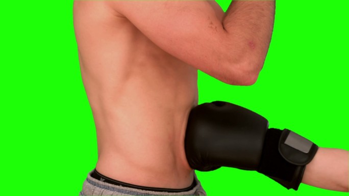 男人在绿色背景下被拳击手套击中特写