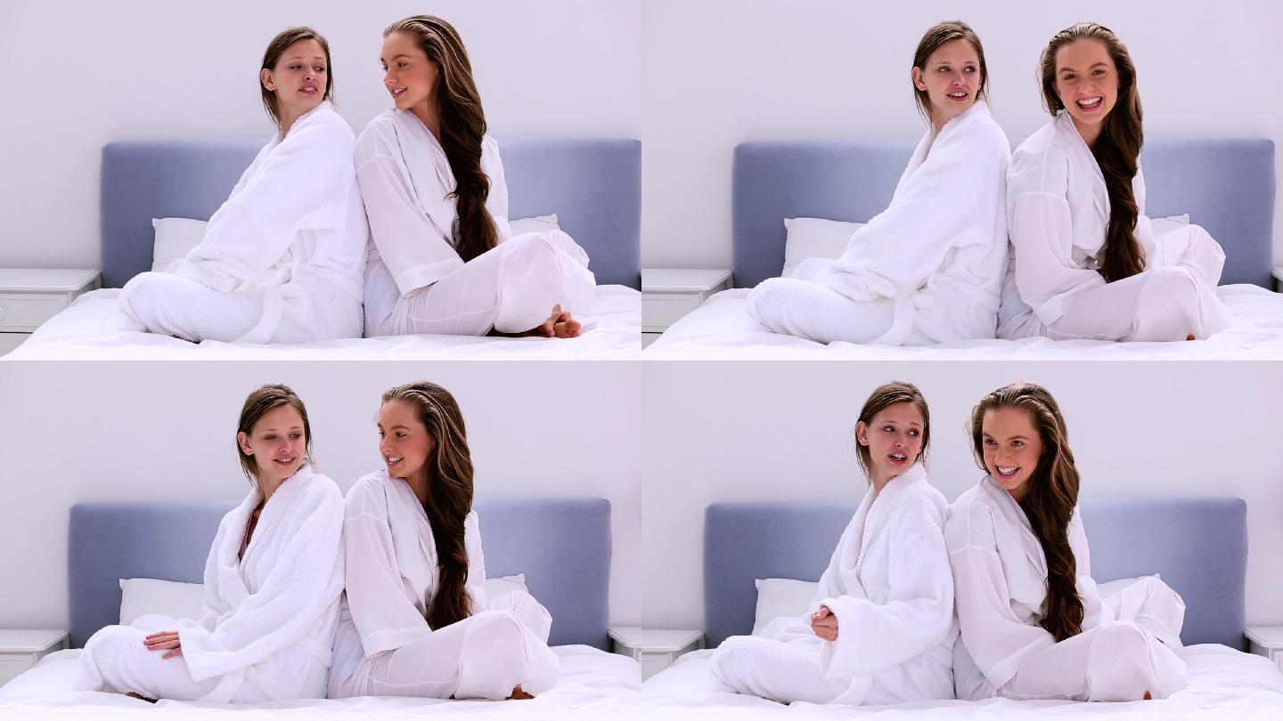 穿着浴袍的女孩们在朋友家过夜时在床上聊天