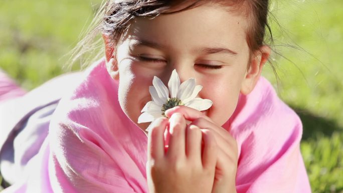 快乐的女孩在公园里拿着一朵美丽的花