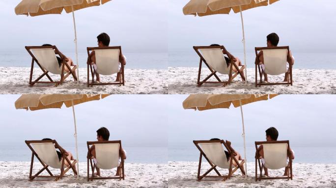 一对情侣躺在沙滩的长椅上特写