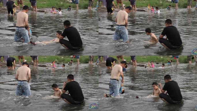 炎热的夏天大人领着小孩子在河中泡澡玩耍