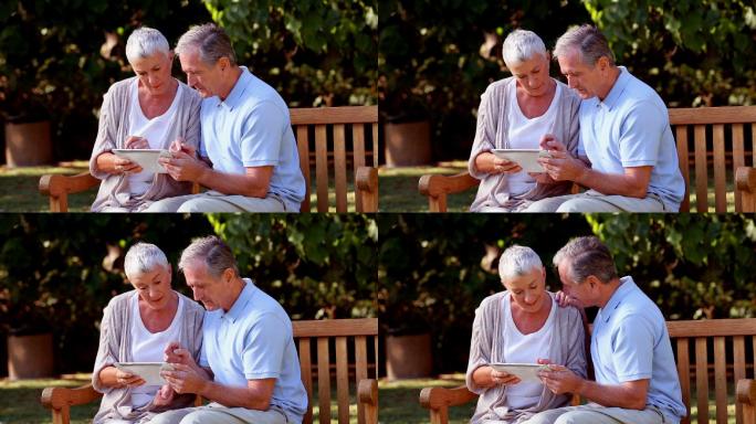 一对老夫妇在公园的长椅上玩平板电脑特写