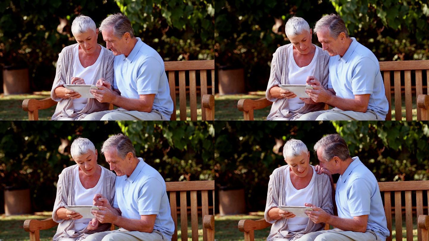 一对老夫妇在公园的长椅上玩平板电脑特写