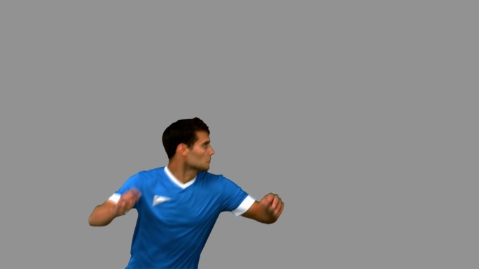 一个足球运动员在灰色背景下练习足球特写