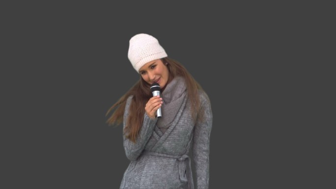 女人穿着冬装在灰色背景下唱歌特写