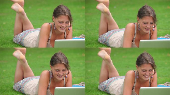 学生坐在校园的草地上用电脑学习特写
