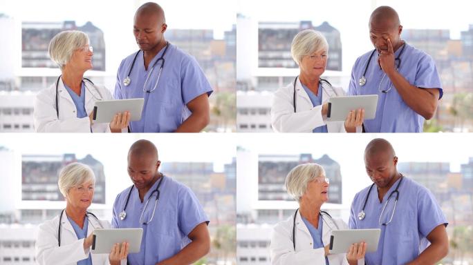 快乐的医生和护士看着平板电脑在一个明亮的房间
