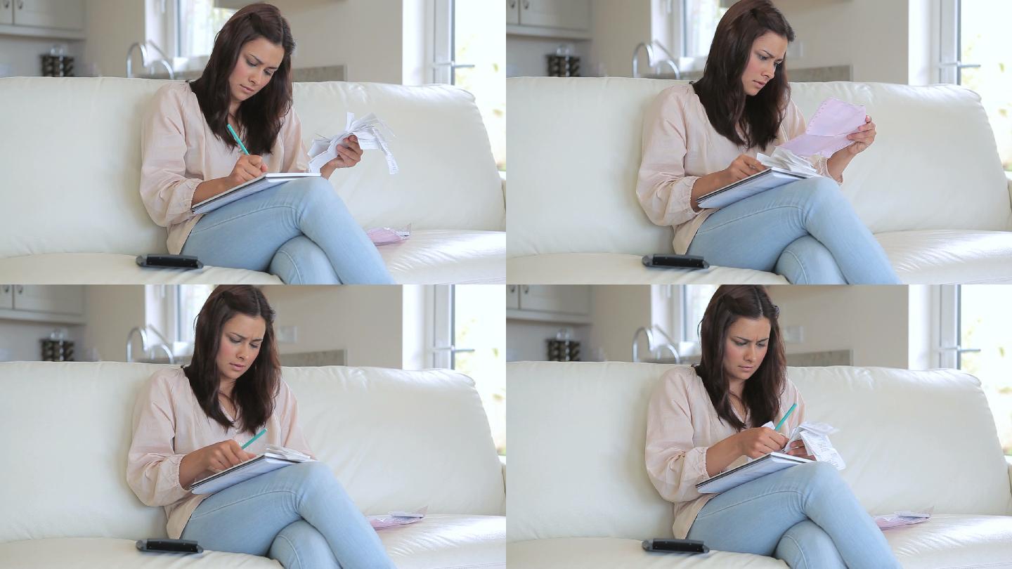 视频显示一个女人坐在客厅的沙发上查看账单