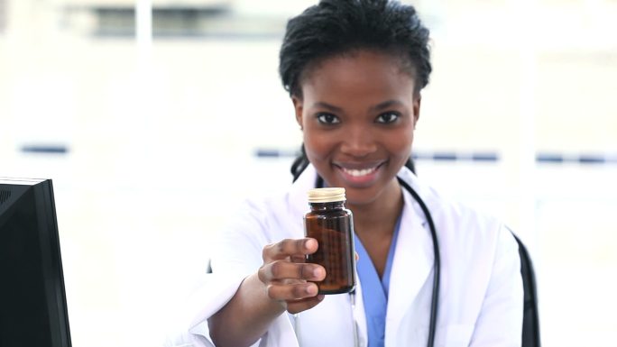 女医生坐在办公桌前展示一个药瓶