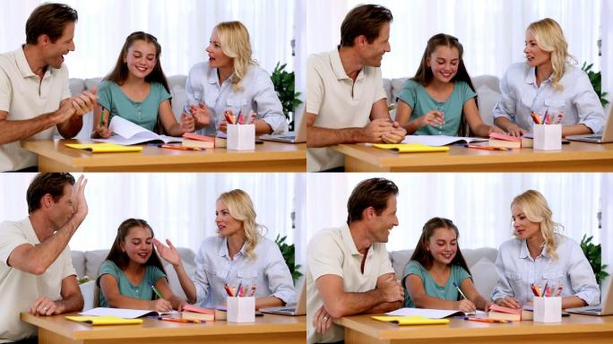 父母为他们的女儿在客厅的书桌上做作业而感到自豪