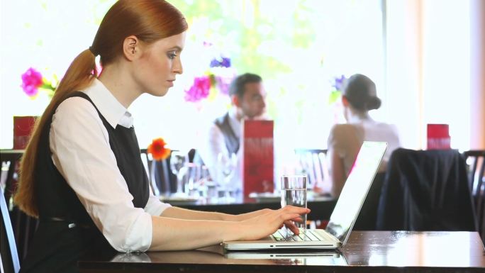 一位严肃的女商人在一家高档餐厅里用笔记本电脑工作