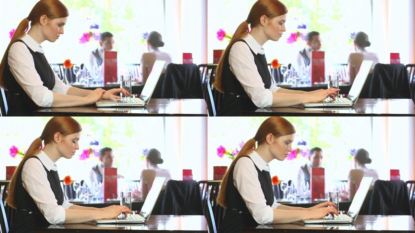 一位严肃的女商人在一家高档餐厅里用笔记本电脑工作