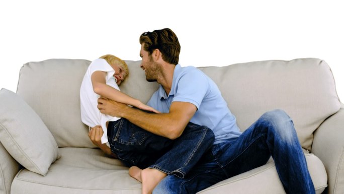 在白色背景的慢动作中，父亲在沙发上挠儿子痒痒