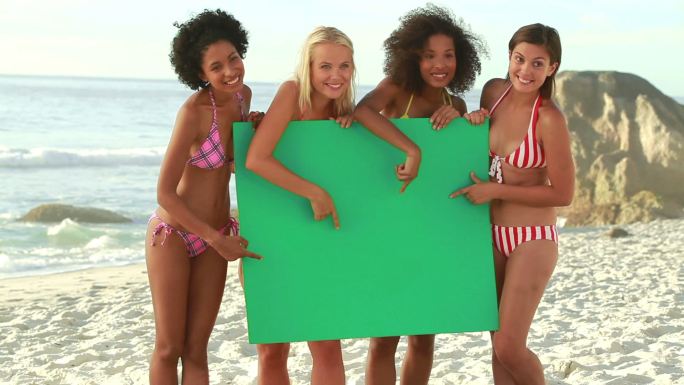 朋友们在沙滩上抱着绿色板子特写